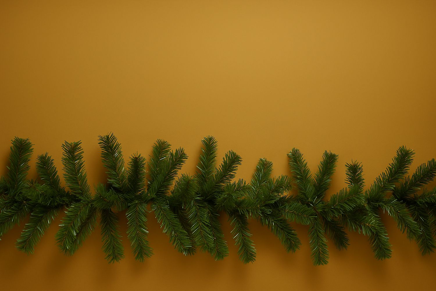 Üppige grüne Tannengirlande mit feinen Nadeln liegt horizontal auf einem warmen goldenen Hintergrund.